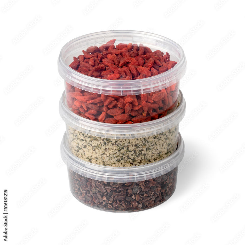 Three plastic containers with superfood, dried goji berries , cacao nibs and hemp seed on white background