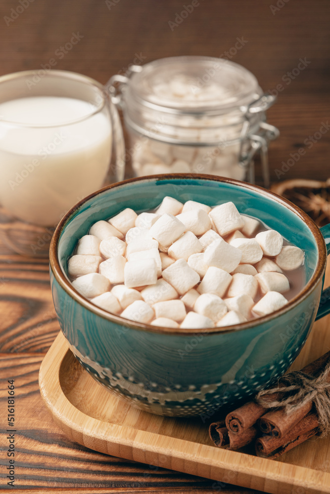 Cup of tasty cocoa drink and marshmallows in blue cup.Spices and marshmallows for winter drinks on brown texture table.Winter hot drink.Hot chocolate with marshmallow and spices.Copy space. Cup of tasty cocoa drink and marshmallows in blue cup.Spices and marshmallows for winter drinks on brown texture table.Winter hot drink.Hot chocolate with marshmallow and spices.Copy space.