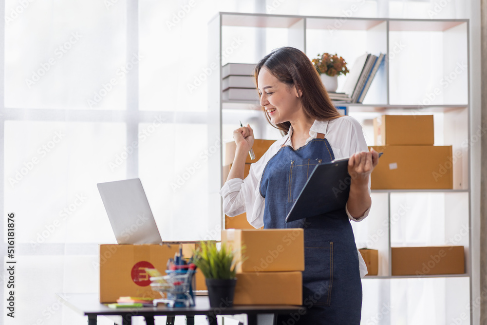 Startup SME small business entrepreneur of freelance Asian woman using a laptop with box Cheerful success happy Asian woman her hand lifts up online marketing packaging and delivery SME idea concept Startup SME small business entrepreneur of freelance Asian woman using a laptop with box Cheerful success happy Asian woman her hand lifts up online marketing packaging and delivery SME idea concept