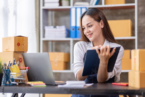 Startup SME small business entrepreneur of freelance Asian woman using a laptop with box Cheerful success happy Asian woman her hand lifts up online marketing packaging and delivery SME idea concept