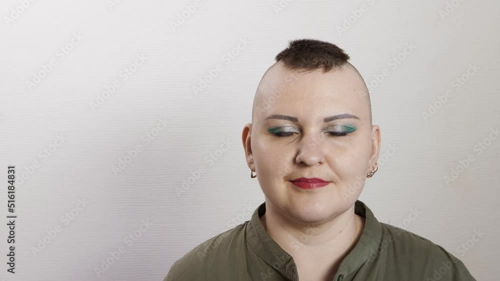 A shaven woman with a mohawk smiles showing class ok to the camera. Medium plan A shaven woman with a mohawk smiles showing class ok to the camera. Medium plan