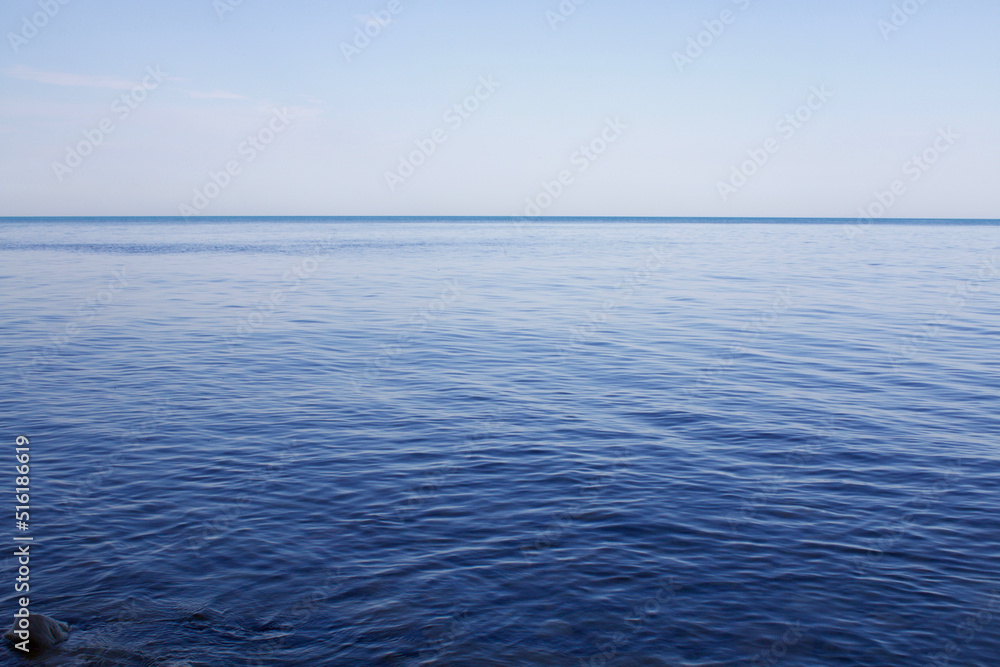Blue sky and sea. The flat surface of a calm sea at dawn.