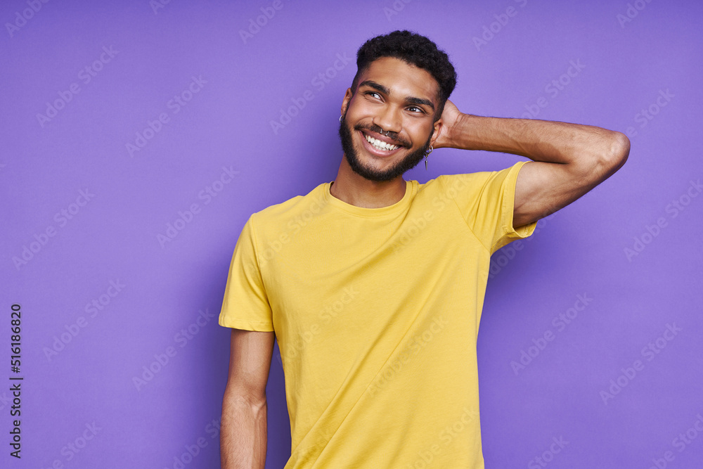 Thoughtful African man holding hand behind head while standing against purple background Thoughtful African man holding hand behind head while standing against purple background