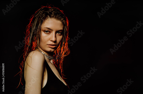 Portrait of young beautiful girl brunette, amid spotlight. night club, dance culture, black background and red lights