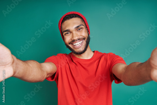 Happy African man stretching out hands while standing against green background