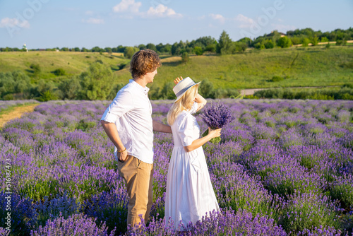 couple in white outfit in lavender field, photo session. man is proposing to woman with ring. engagement day. romance and true love in relationship