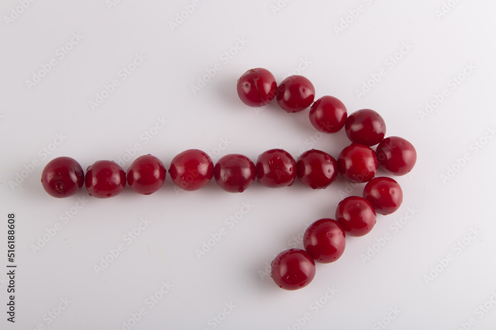 Cherry arrow on white background. Top view on fresh wet red fruits lay in shape of pointer to right. Cherry arrow on white background. Top view on fresh wet red fruits lay in shape of pointer to right.