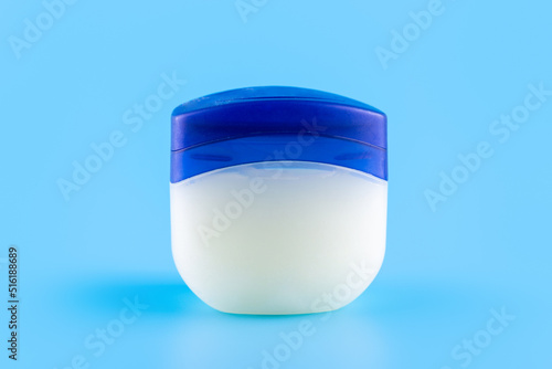 Vaseline or petroleum jelly in a clear jar on blue background with copy space for text. Skin care ointment