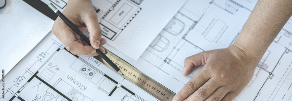 Engineer and Architect concept, Man uses a ruler to measure the floor plan on the blueprint, Building architecture design work, Construction design project under environmental conservation conditions. Engineer and Architect concept, Man uses a ruler to measure the floor plan on the blueprint, Building architecture design work, Construction design project under environmental conservation conditions.
