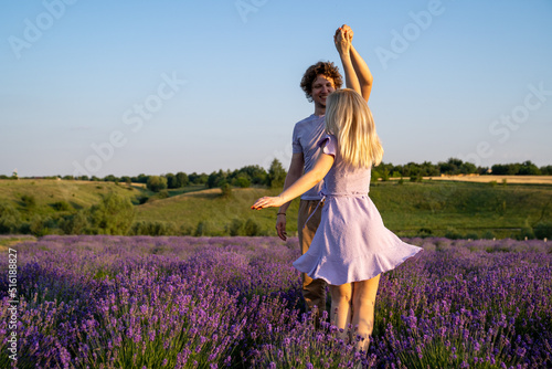Fototapeta Naklejka Na Ścianę i Meble -  romantic couple in purple outfit in love dancing together in lavender field 