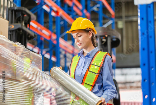 Bilde på lerret Female worker wrapping boxes in stretch film at warehouse, Worker wrapping stret