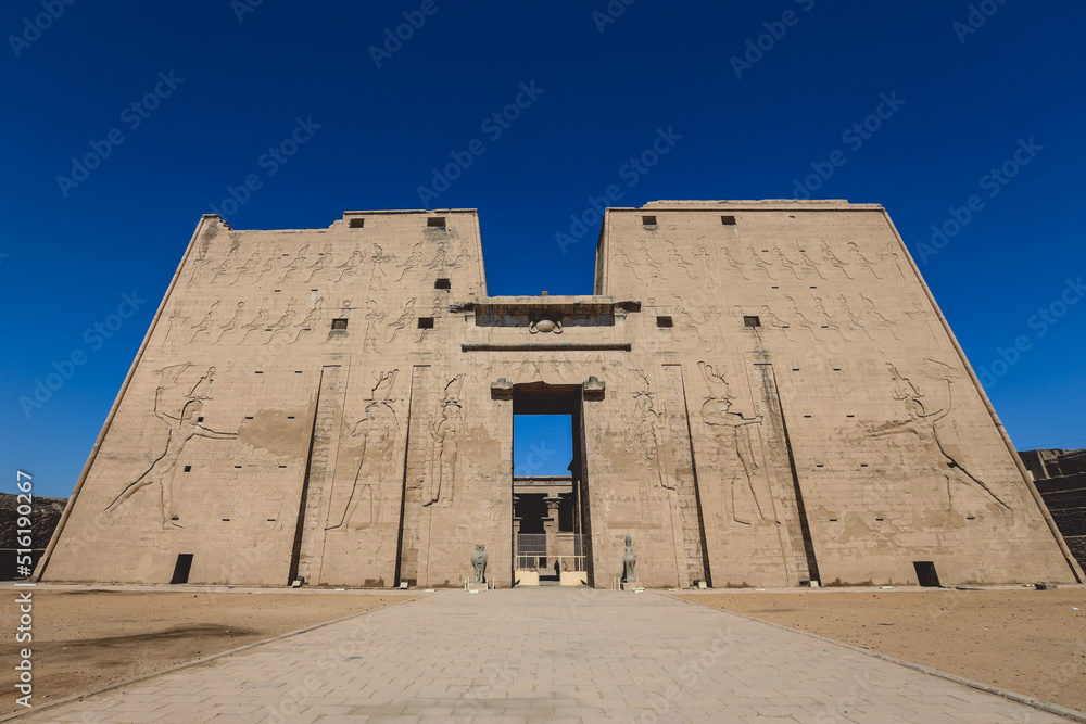 View to the main entrance of an Ancient Egyptian Edfu Temple showing the first pylon in the Sunny Day, Egypt View to the main entrance of an Ancient Egyptian Edfu Temple showing the first pylon in the Sunny Day, Egypt