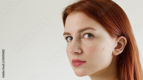 Very attractive red-haired young woman looks into the camera. Close up