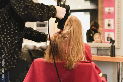 Hairdresser dries hair with a hairdryer at a saon