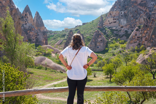 Back turned woman with white tshirt looking landscape, fairy chimneys, cave dwellings and rural view of Goreme National Park, Cappadocia, Nevsehir Turkey.