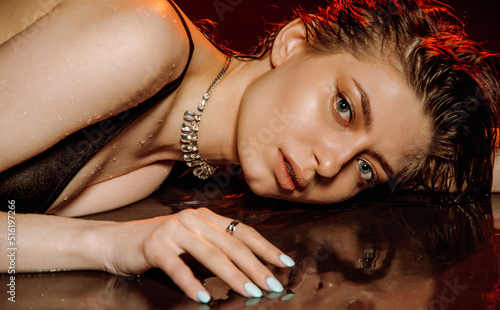 Young girl with wet, damp hair , big eyes and naked shoulders posing at dark red studio background