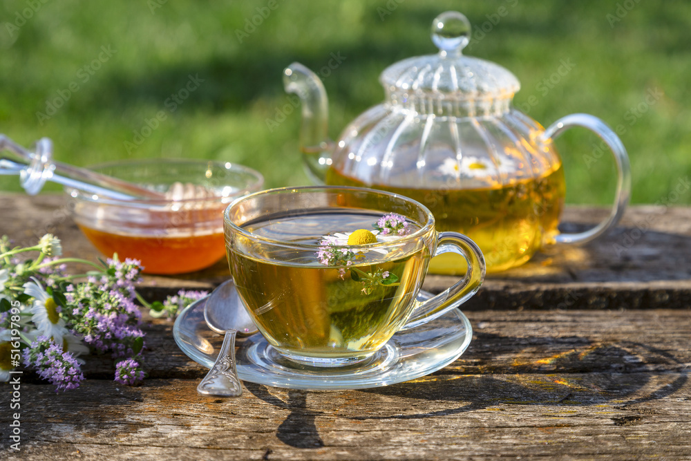 Herbal tea with chamomile and thyme in a transparent cup on an old wooden table on a sunny day Herbal tea with chamomile and thyme in a transparent cup on an old wooden table on a sunny day