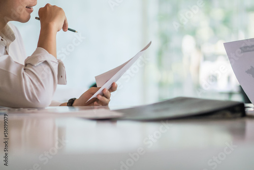 Photography An accountant is examining a large amount of income and expense documents laying on their desks in their offices to summarize their annual results