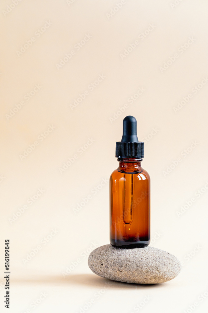 Amber glass dropper bottle with black lid on a podium on stones. Skincare products , natural cosmetic. Beauty concept for face and body care Amber glass dropper bottle with black lid on a podium on stones. Skincare products , natural cosmetic. Beauty concept for face and body care