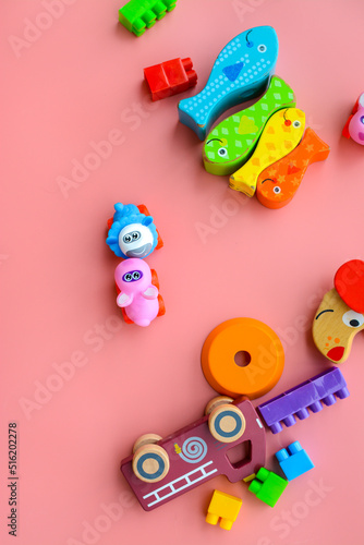 Child is playing with colorful wooden and plastic toys, on pink background © Edita