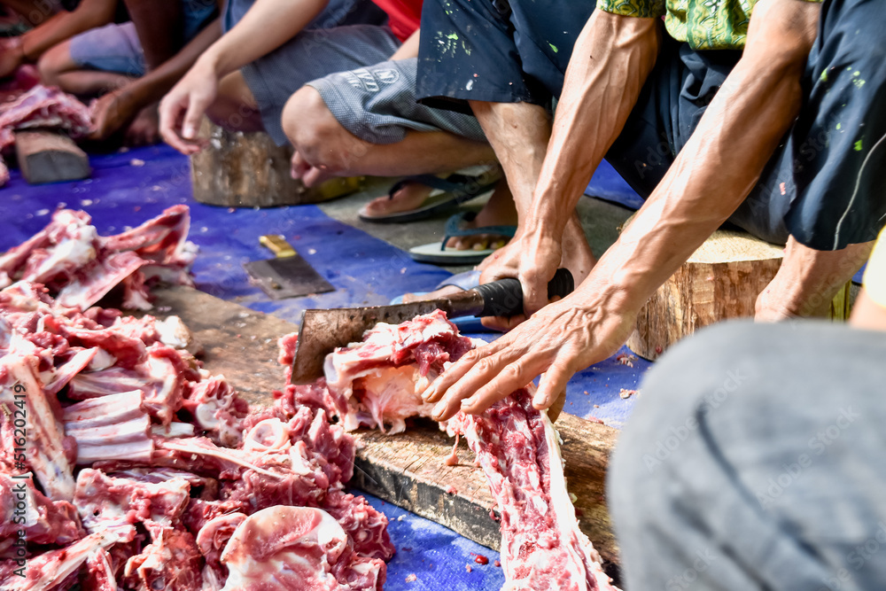 Men cut the meat into small pieces on Eid al-Adha. Feast of Qurban during Eid Al Adha Al Mubarak. Mojotengah - Wonosobo, Central Java, Indonesia. July 10, 2022.