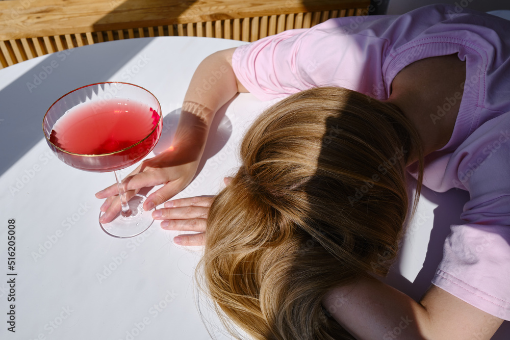 Naklejka premium The girl fell asleep over glasses of red wine. Tasting of alcoholic beverages. Summer rest. Romantic evening aperitif. Close-up of a glass of wine 