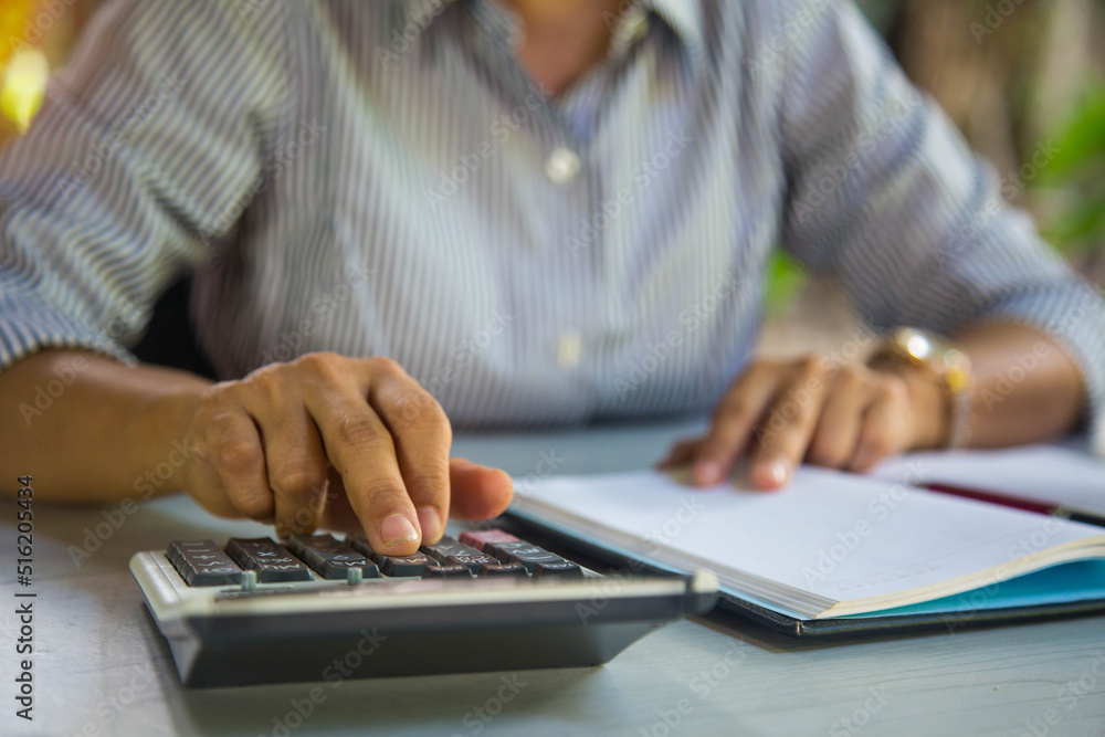 Business woman using calculator finance on wooden desk in home office Business woman using calculator finance on wooden desk in home office