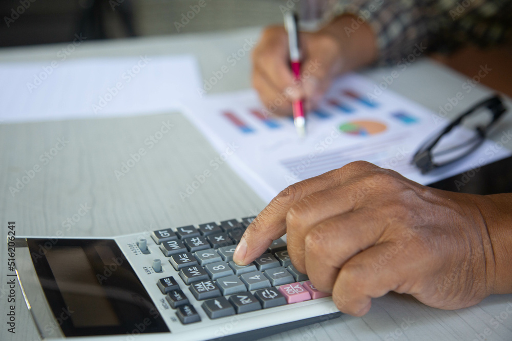 Close up Business man using calculator finance on wooden desk in home office.concept Close up Business man using calculator finance on wooden desk in home office.concept