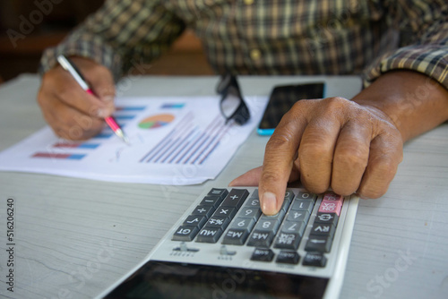 Close up Business man using calculator finance on wooden desk in home office.concept