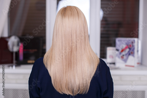 Female back with long straight natural blonde hair in hairdressing salon