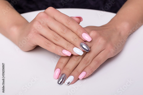 Beautiful female hands with colourful manicure nails, pink and silver colored gel polish 