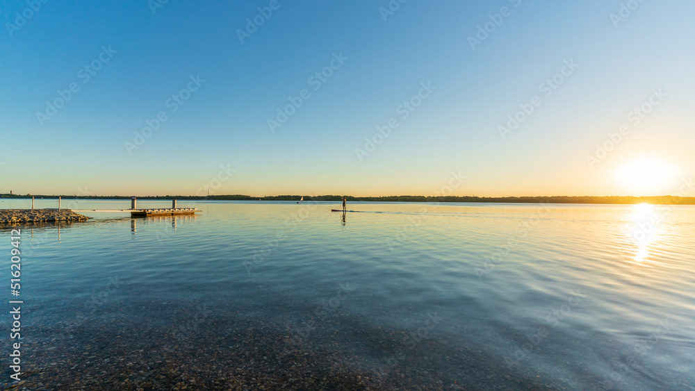 A stand up paddler on a lake at a beautiful sunset
