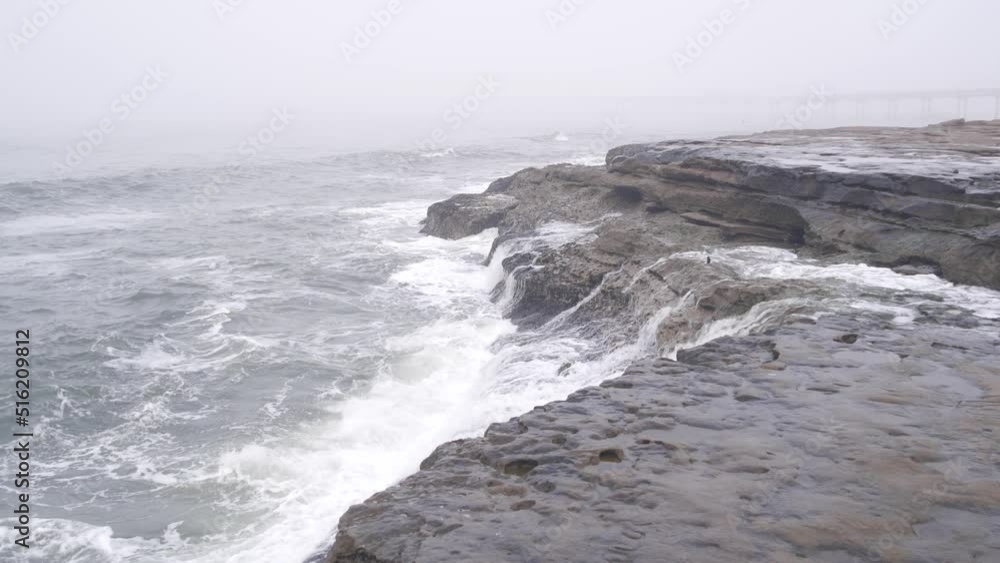 Foggy sea landscape, waves crashing on ocean beach in haze, misty weather. Calm tranquil moody atmosphere, grey monochrome seascape, gloomy dramatic shore cliffs or coast rocks. stormy water surface. Foggy sea landscape, waves crashing on ocean beach in haze, misty weather. Calm tranquil moody atmosphere, grey monochrome seascape, gloomy dramatic shore cliffs or coast rocks. stormy water surface.