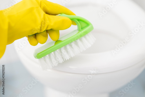 a girl in gloves washes a toilet seat in gloves with a brush