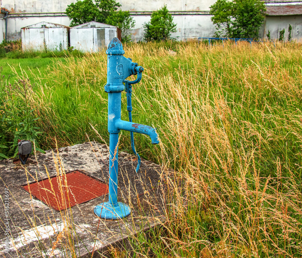 Retro borehole pump on a sunny day, old manual water pump (lever pump). Old cast iron water pump in Slovakia in the city of Nitra.