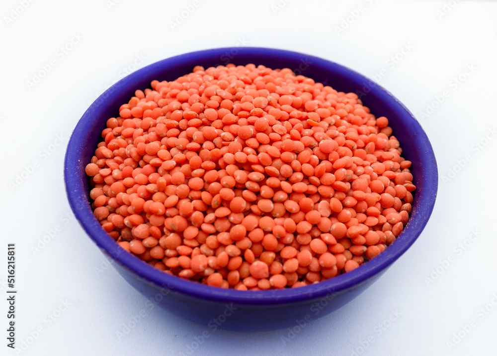 Pile of Red lentils or Musur Dal Beans in a blue bowl Pile of Red lentils or Musur Dal Beans in a blue bowl