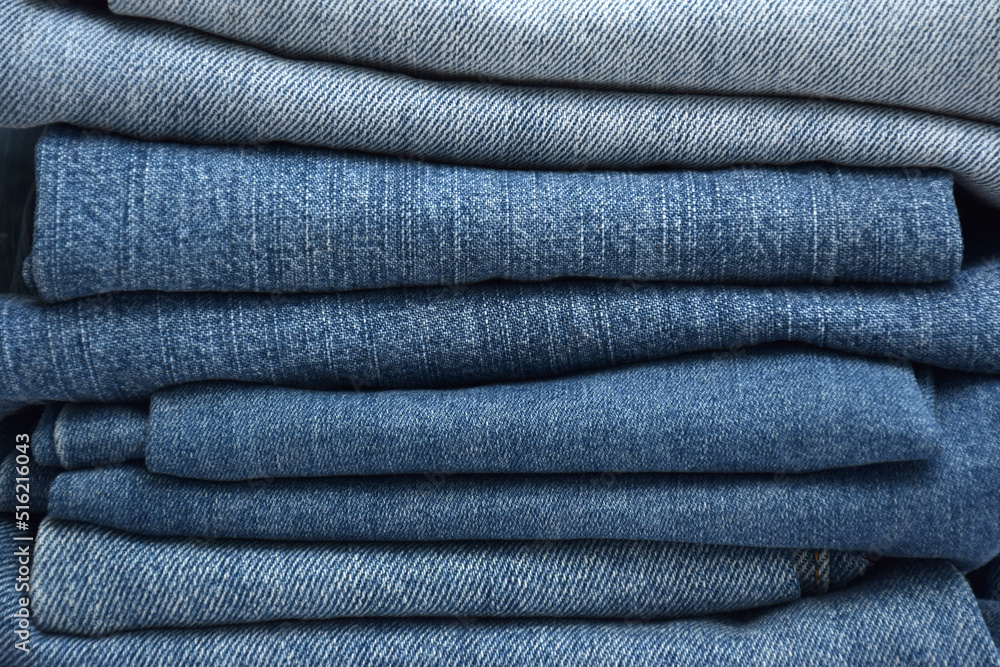 Lots of jeans pants in a stack. Denim background. Lots of jeans pants in a stack. Denim background.