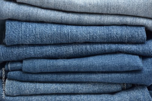 Lots of jeans pants in a stack. Denim background.