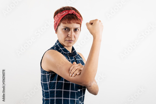 a mid age Latin woman mimicking the pose of Rosie the Riveter