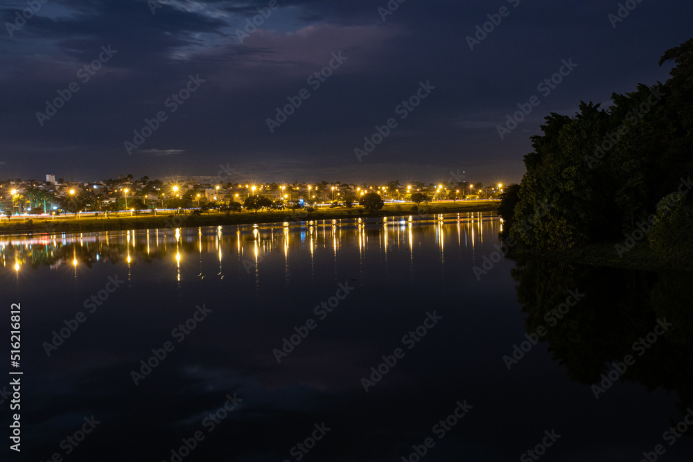 Colors of city lights reflecting in the municipal dam of Sao Jose do Rio Preto during dusk on cloudy night