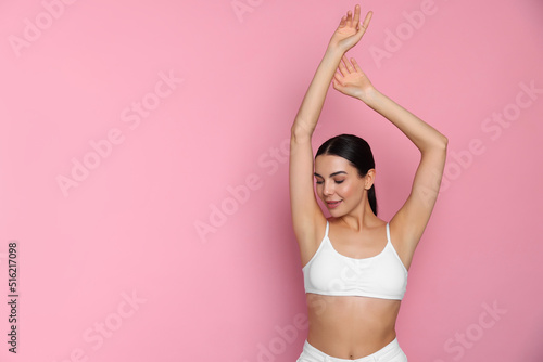 Young woman showing smooth skin after epilation on pink background, space for text photo