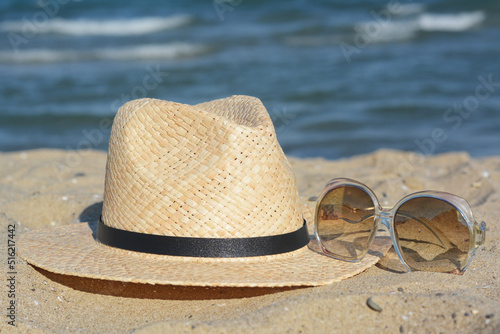 Stylish straw hat and sunglasses on sandy beach © New Africa