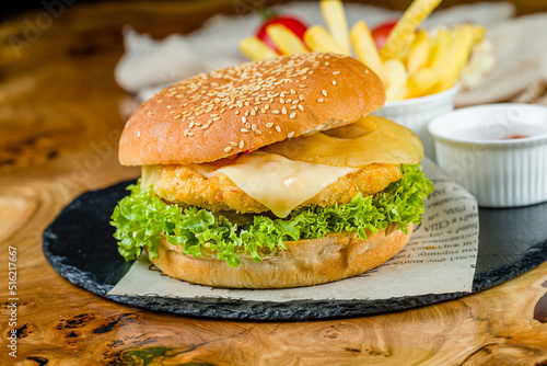 Burger with fish patty, cheese and pine apple on wooden table