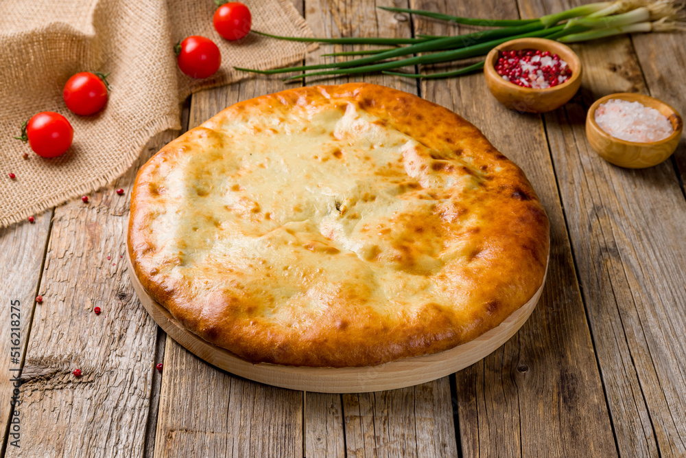 Ossetian pie with spinach on old wooden table Ossetian pie with spinach on old wooden table
