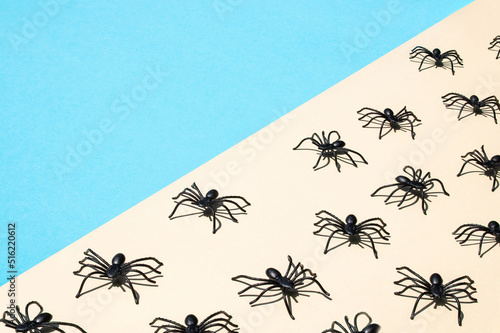 Sunlight pattern made of spiders on a bright pastel beige and blue background. Minimal summer insects concept. Side view. Hard shadows.