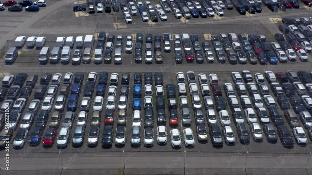 Aerial top view of many cars parked. Aerial shot above a parking area full of cars. multicolored cars on warehouse parking lot. Dealership car lot. Aerial top view of many cars parked. Aerial shot above a parking area full of cars. multicolored cars on warehouse parking lot. Dealership car lot.