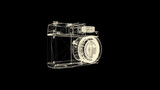 Old fashioned photo camera hologram rotating on black background. Yellow camera wireframe spinning and falling apart into the dust.