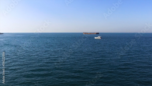 Aerial view of beautiful seascape with white yacht and dark barge on blue sky background. Stock. Beautiful calm sea in a sunny day with two floating vessels. © Media Whale Stock