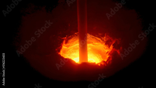 Close up of a hole in melting furnace with a rotating rod, metallurgical industry concept. Stock footage. Process of metal melting at the plant.