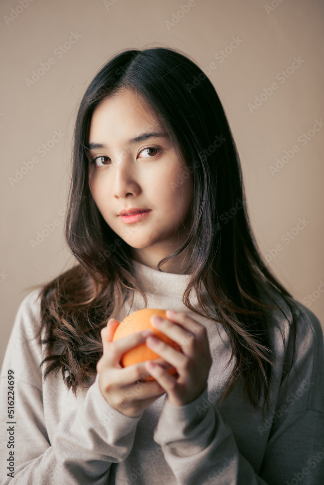 attractive cheerful asian woman holding orange or grapefruit , beauty and healthy skin care and cosmetic ideas concept attractive cheerful asian woman holding orange or grapefruit , beauty and healthy skin care and cosmetic ideas concept